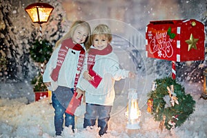 Cute blond children, boy and girl, siblings, posting Christmas letter to Santa Claus, winter day