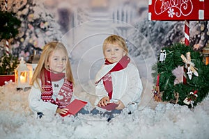 Cute blond children, boy and girl, siblings, posting Christmas letter to Santa Claus, winter day