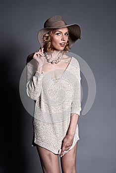 Cute blond fashion model in stretchy knitwear top and hat posing