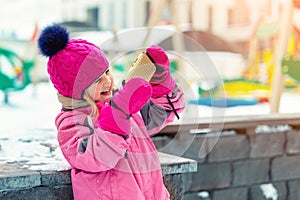 Cute blond kid girl holding smartphone and streaming for social networks winter fun activities at playground outdoor. Funny