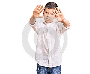 Cute blond kid wearing elegant shirt doing frame using hands palms and fingers, camera perspective