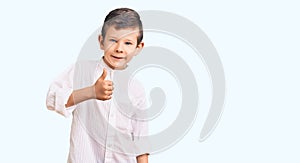 Cute blond kid wearing elegant shirt doing happy thumbs up gesture with hand