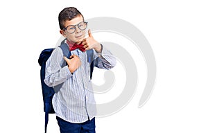 Cute blond kid wearing nerd bow tie and backpack smiling happy and positive, thumb up doing excellent and approval sign