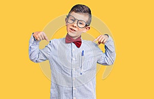 Cute blond kid wearing nerd bow tie and glasses looking confident with smile on face, pointing oneself with fingers proud and
