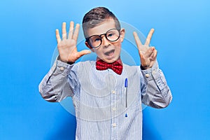 Cute blond kid wearing nerd bow tie and glasses showing and pointing up with fingers number seven while smiling confident and
