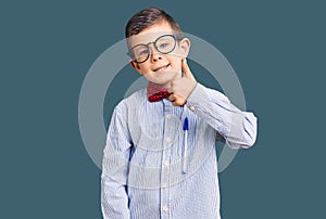 Cute blond kid wearing nerd bow tie and glasses smiling happy and positive, thumb up doing excellent and approval sign