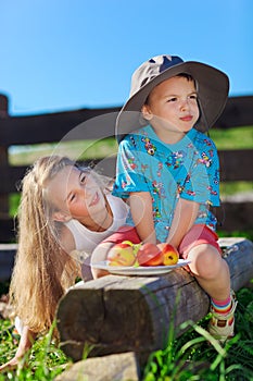 Cute blond little girl and boy playing with fruits