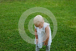 Cute blond lond baby girl playing on the grass