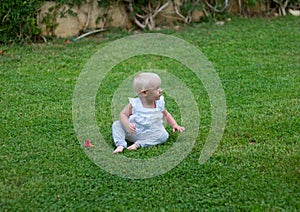 Cute blond lond baby girl playing on the grass photo