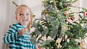 Cute blond preschool girl decorating christmas tree. Authentic family xmas time