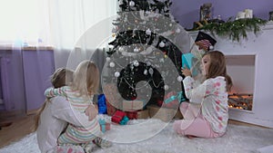 Cute blond sibling sisters in pajamas are searching for presents