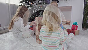 Cute blond sibling sisters in pajamas are searching for presents