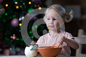 Cute blond toddler girl with blue eyes having her meal in christmas entourage