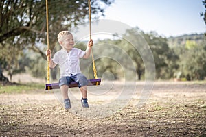 Cute blond toddler on the swing