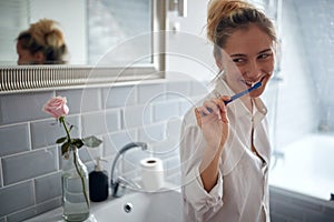 Cute blond woman brushing teeth