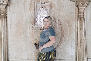 Cute blond woman tourist 30s poses by an oranate window near marble pillars in a city palace in Udaipur India