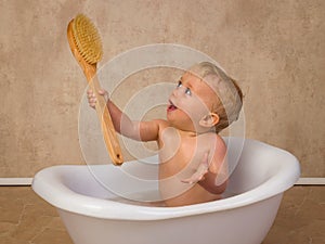 Cute blonde baby boy happy with big brush