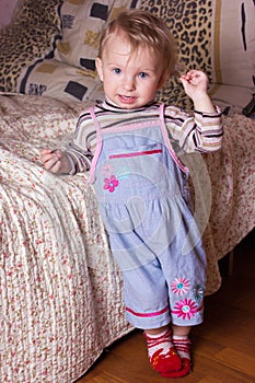 Cute blonde baby girl with beautiful blue eyes sitting and smiling with toy