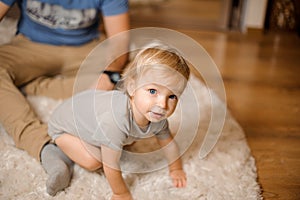 Cute blonde and blue-eyed baby dressed in a grey romper
