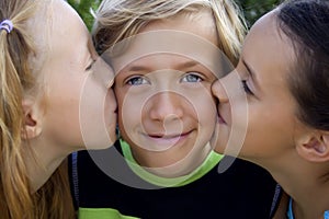 Cute blonde boy kissed by two girls photo