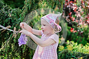 Cute blonde child girl plays toy wash in summer garden