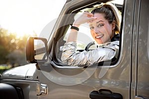 Cute blonde female driver portrait, smiling and happy driving through outdoor national park, through nature, commercial model