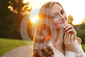 Cute blonde girl on background of sun. Ordinary happy woman enjoying life in summer