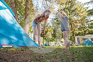 Cute blonde girl helping around tent pitch at camping resort.