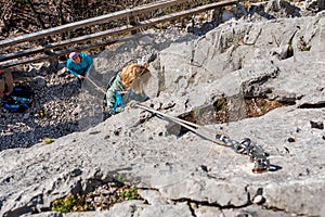 Cute blonde girl rock climbing using top rope with her mother protecting her.