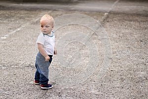 Cute blonde kid looking looking back. Awesome baby boy on the walk. Copy space