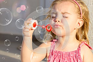 A cute blonde little gir, blowing soap bubbles