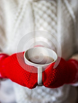 Cute blonde little girl holding hot steaming tea cup close up photo