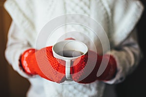 Cute blonde little girl holding hot steaming tea cup close up photo