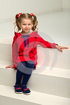 Cute blonde little girl sitting on the stairs