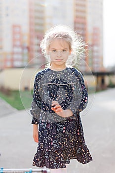 A cute blonde little girl is smiling at the camera. walking outside in the sunlight