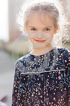 A cute blonde little girl is smiling at the camera. walking outside in the sunlight
