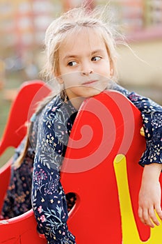 A cute blonde little girl is smiling at the camera. walking outside in the sunlight