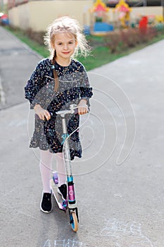 A cute blonde little girl is smiling at the camera. walking outside in the sunlight