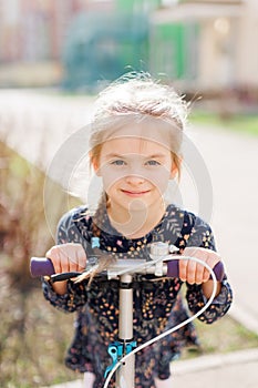 A cute blonde little girl is smiling at the camera. walking outside in the sunlight