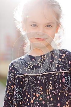 A cute blonde little girl is smiling at the camera. walking outside in the sunlight