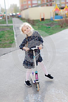 A cute blonde little girl is smiling at the camera. walking outside in the sunlight