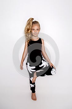 Cute blonde little girl in sport outfit on a white background in studio.