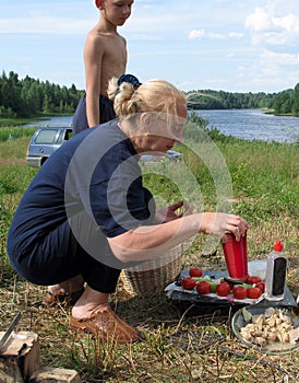 Cute blonde mature woman preparing vegetable salad in the campaign