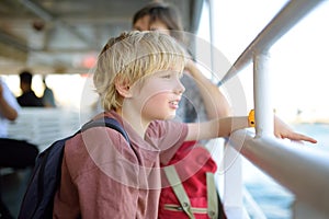 Cute blonde preteen boy is traveling by boat or ferry on the sea. Family vacations on ocean or sea. Summer leisure for families