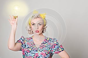 Cute blonde retro girl holding glowing light bulb - humorous con