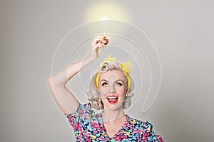 Cute blonde retro girl holding glowing light bulb - humorous con