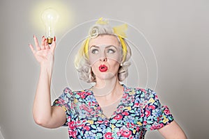 Cute blonde retro girl holding glowing light bulb - humorous con