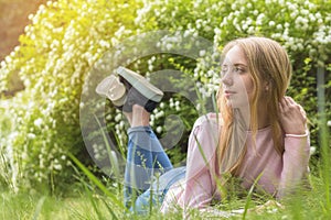 Cute blonde teenage-girl dreaming on a sunny day on the grass