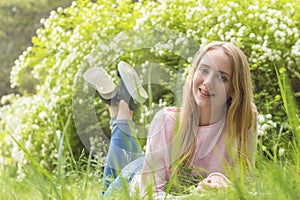 Cute blonde teenage-girl dreaming on a sunny day on the grass