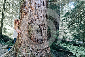 Cute blonde woman hugs a large tree. Taken in Olympic National Park along the Sol Duc Falls trail